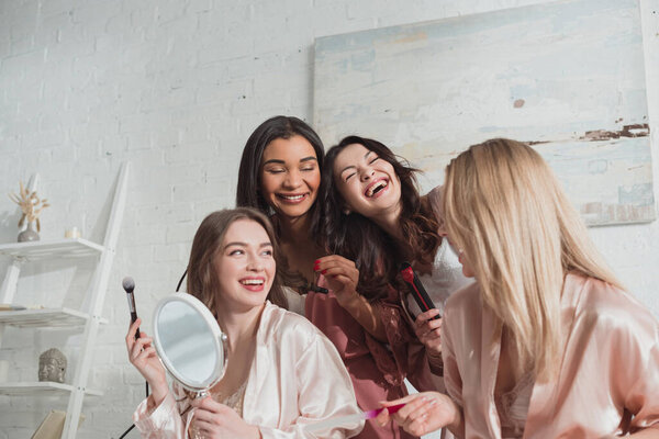 Multiethnic women doing hairstyle, manicure and laughing at bachelorette party