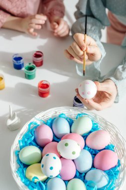 Paskalya yumurtası boyayan anne ve çocuğun kırpılmış görüntüsü. 