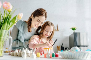 Lalelerin ve paskalya yumurtalarının yanında mutlu anne ve çocuğun seçici odağı 