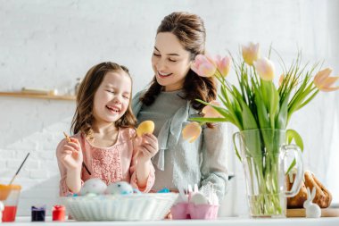 Lalelerin, tavuk yumurtalarının ve paskalya ekmeğinin yanında mutlu anne ve kızın seçici odağı