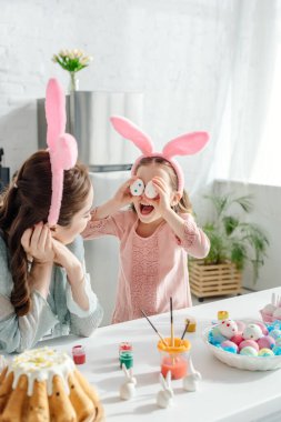 Annenin tavşan kulaklı şirin kızına bakıp gözlerini paskalya yumurtasıyla kapattığı seçici odak noktası. 