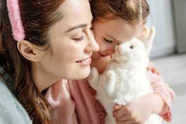 Mutlu anne ve oyuncak tavşanı olan sevimli çocuğun seçici odağı. 