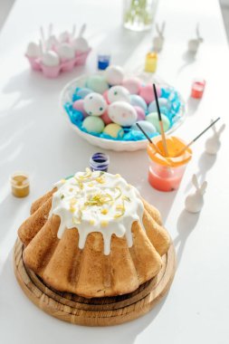 Boyalı tavuk yumurtaları ve dekoratif tavşanların yanında tatlı paskalya pastasının seçici odağı. 