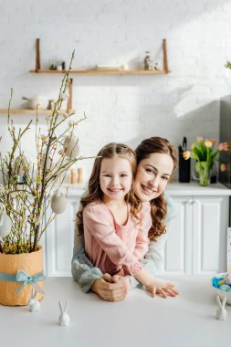 Mutlu anne ve kız çiçek saksısı ve dekoratif tavşanlar içinde söğüt ağacının yanında 
