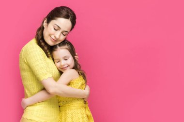 Neşeli anne ve kız gözleri kapalı pembe üzerine izole edilmiş sarılıyorlar. 