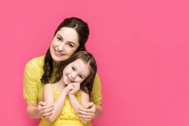 Neşeli anne kucaklayan sevimli kız pembe üzerinde izole 