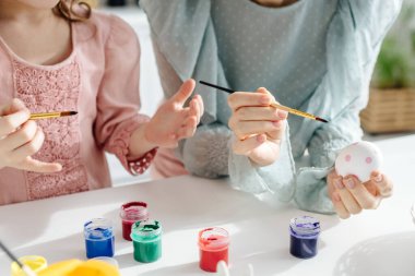 Anne ve kızının tavuk yumurtası resmedilmiş görüntüsü. 