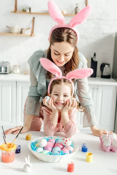 Щаслива Мати Дивиться Вуха Кролика Дочку Біля Великодніх Яєць — стокове фото