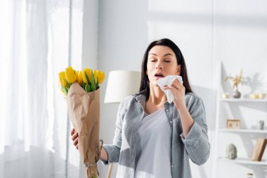 attractive woman with pollen allergy sneezing while holding tulips  clipart