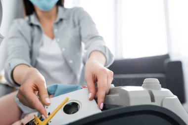 Tıbbi maskeli, elektrikli süpürgenin yanında toz torbası tutan alerjik kadın görüntüsü.