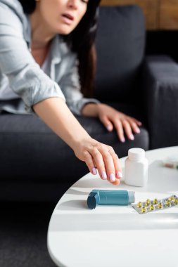 Sehpanın üzerinde ilacın bulunduğu su toplayıcı paketin yanında solunum cihazına uzanan bir kadın görüntüsü. 