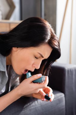 woman with asthma using inhaler at home  clipart