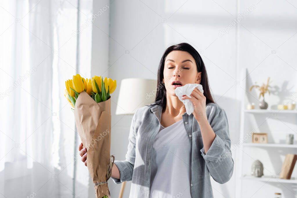 attractive woman with pollen allergy sneezing while holding tulips 
