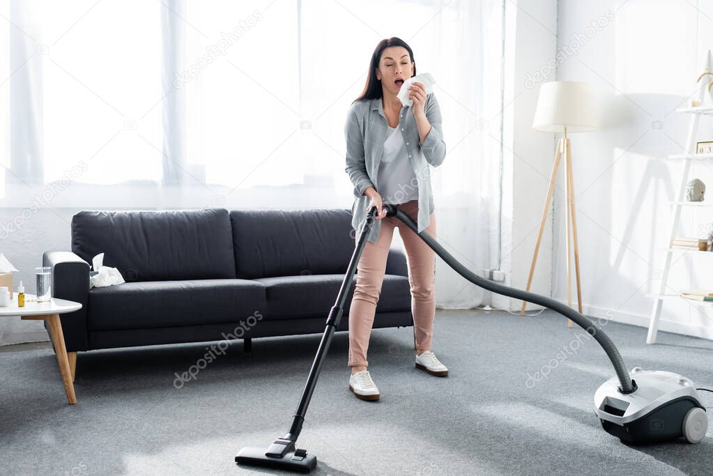 allergic woman sneezing and holding vacuum cleaner 