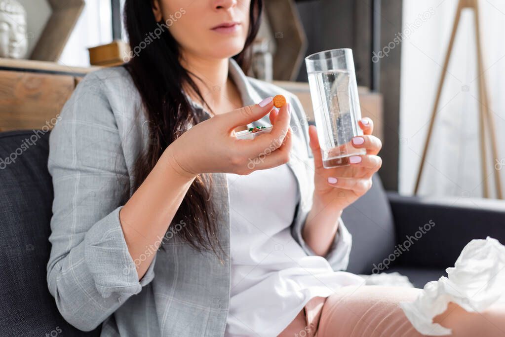 cropped view of allergic woman holding pill and glass of water 