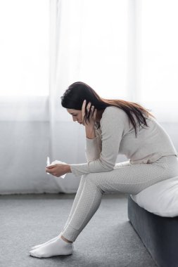 Depresyonda olan kadın yatakta oturuyor ve hamilelik testine negatif sonuç veriyor. 