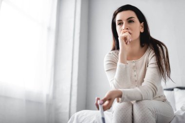 Depresyonda olan kadın yatakta oturuyor ve hamilelik testi negatif sonuç veriyor. 