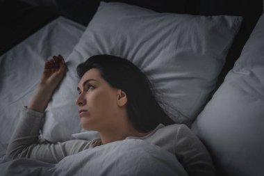 Uykusuzluk çeken ve yatakta yatan hoşnutsuz bir kadın. 