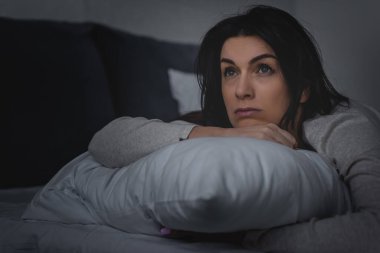 selective focus of dissatisfied woman having insomnia while lying on bed at night  clipart