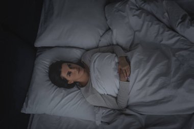 Yatak odasında yatan uyku bozukluğu olan bir kadın. 
