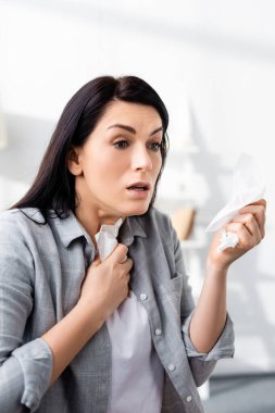 Alerjisi olan şok olmuş bir kadın peçete tutuyor.  