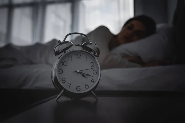 Επιλεκτική Εστίαση Του Ξυπνητήρι Στο Κομοδίνο Σχεδόν Ξύπνια Γυναίκα — Φωτογραφία Αρχείου