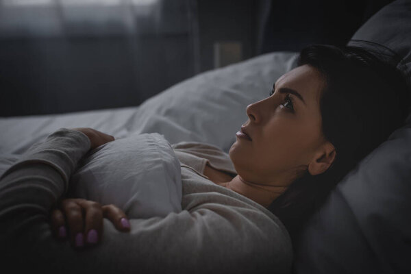 attractive woman having insomnia while lying on bed 