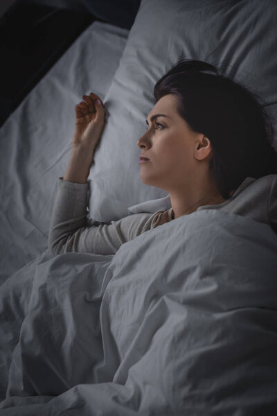 top view of upset woman having insomnia and lying on bed 