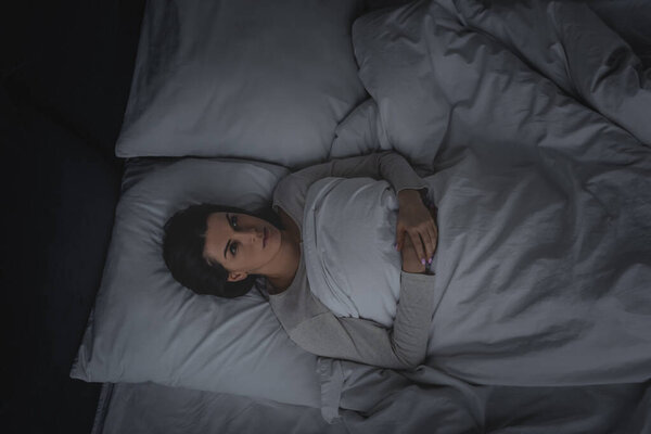 верхний вид женщины с расстройством сна лежит в спальне
 