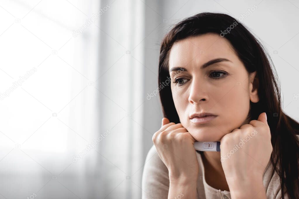 disappointed woman holding pregnancy test with negative result 