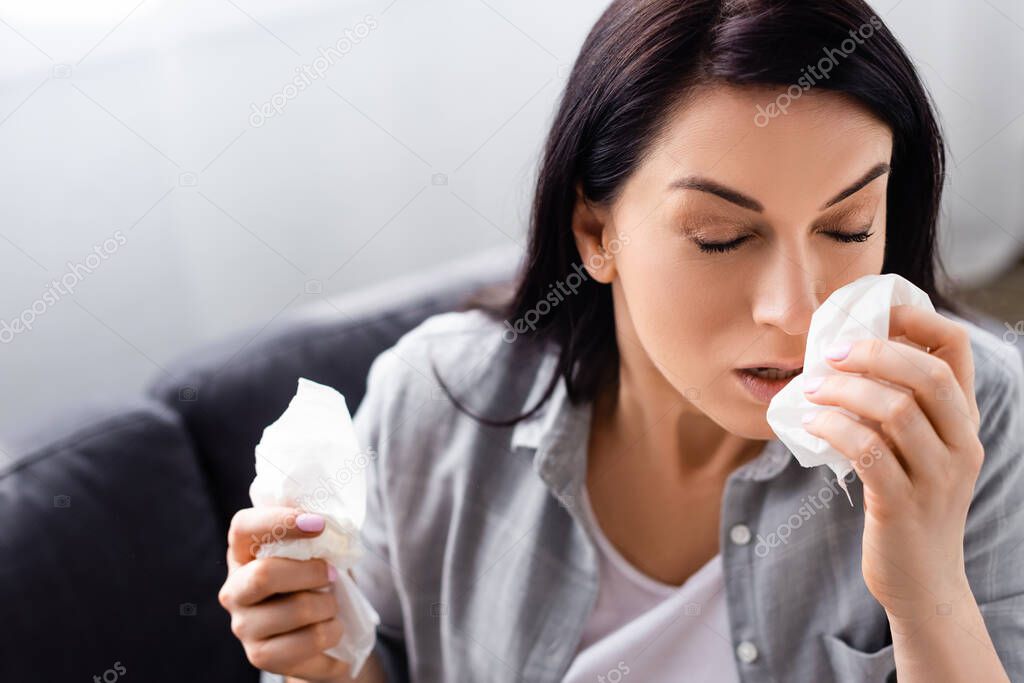 allergic woman with closed eyes holding tissues 