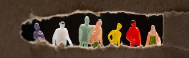 Panoramic shot of cardboard with hole and people figures isolated on black, concept of social equality clipart