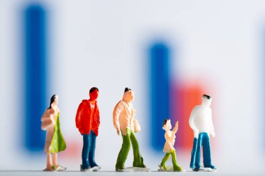 Selective focus of row of people figures on white surface with graphs at background, concept of equality clipart