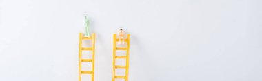 Panoramic shot of two people figures on ladders on white background, concept of equality rights  clipart