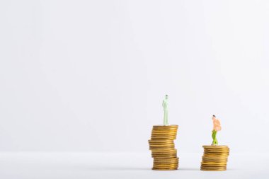 Beyaz yüzeye istiflenmiş paraların üzerindeki iki kişi gri madeni eşitlik kavramını izole etti.