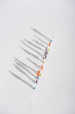 Top view of row of plastic people figures with shadow on white surface clipart