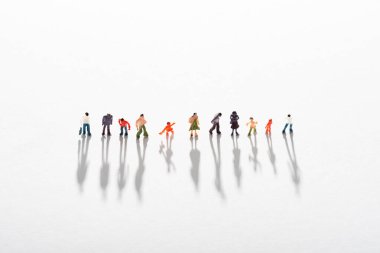 High angle view of row of plastic people figures with shadow on white surface clipart