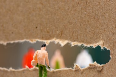 Kartondaki deliğe yakın bebeğin seçmeli odak noktası ve arka planda insan figürlerinin siluetleri