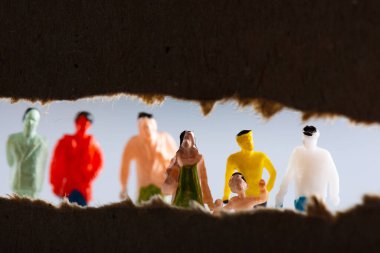Selective focus of cardboard with hole and people figures isolated on grey clipart