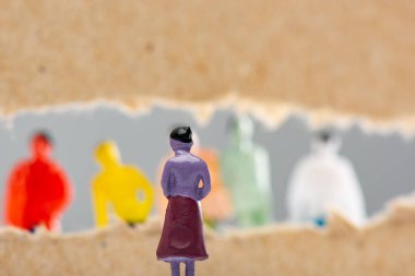 Selective focus of toy near hole in cardboard with people figures isolated on grey, concept of social rights  clipart