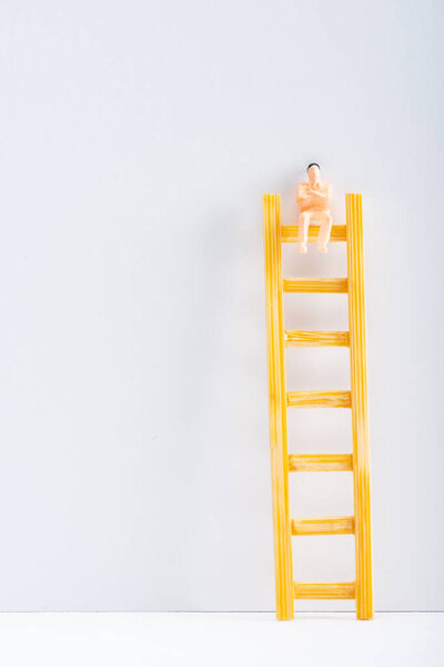 Close up view of doll on ladder on white surface on grey background, concept of equality rights 