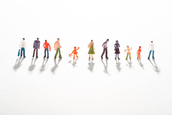 Close up view of row of people figures on white surface with shadow