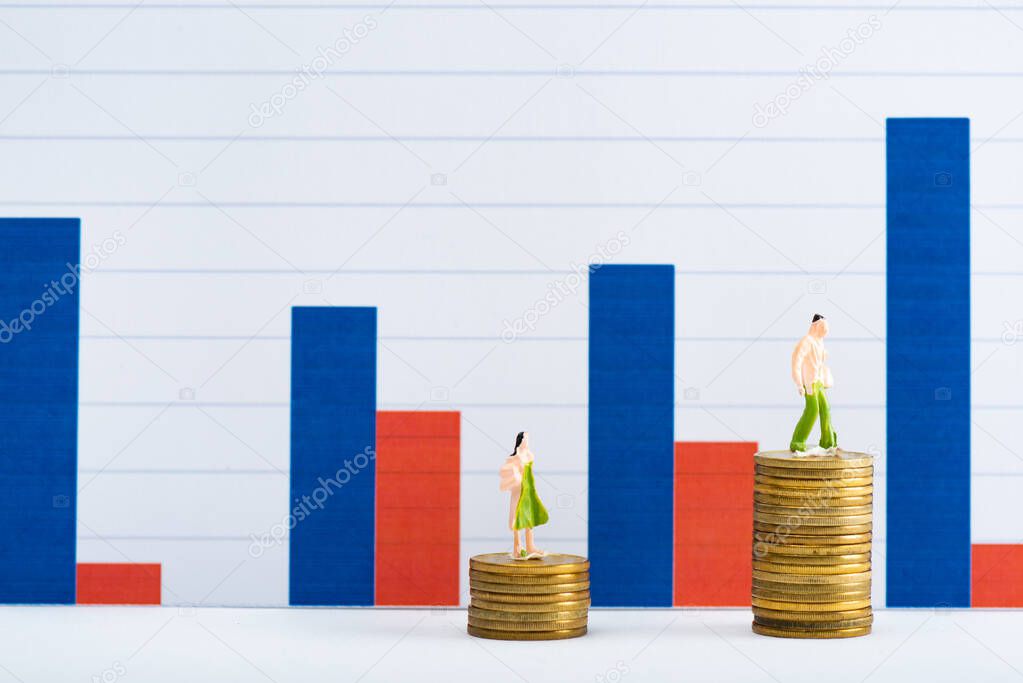 People figures on coins on white surface with charts at background, concept of financial equality