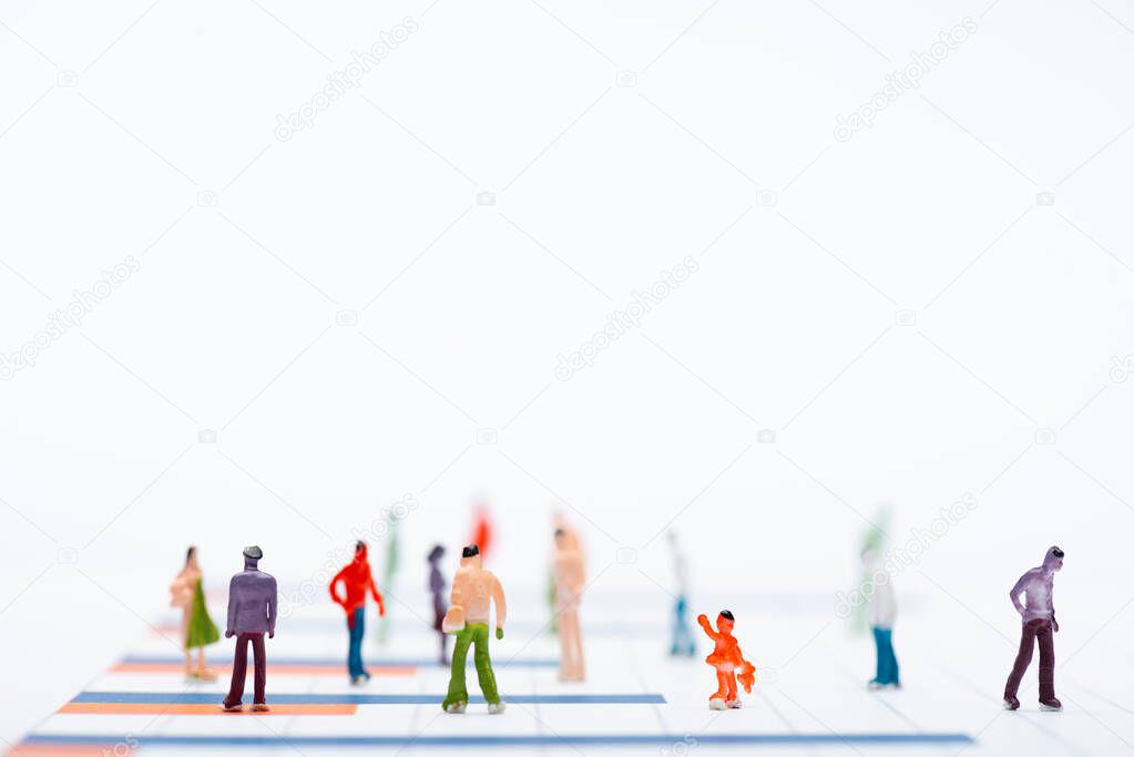 Close up view of plastic people figures on surface with graphs isolated on white, equality concept