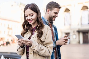 Woman and man smiling and chatting with smartphones