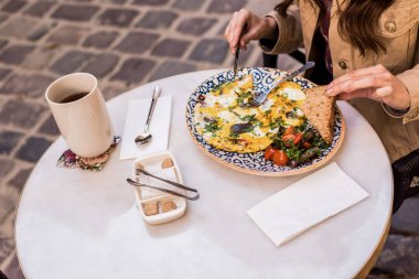 Kafede ekmek ve salatayla omlet yiyen kadının kısmi görüntüsü 