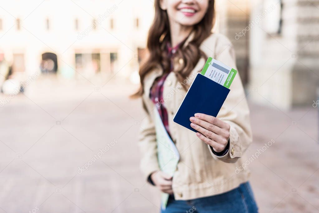 Cropped view of woman smiling and showing passport with air ticket