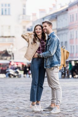 Boyfriend and girlfriend looking away and smiling in city clipart