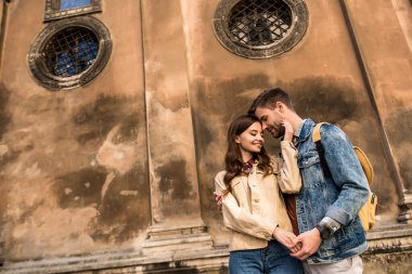 Mutlu çiftin birbirine sarılıp el ele tutuşmasının alçak açılı görüntüsü. 