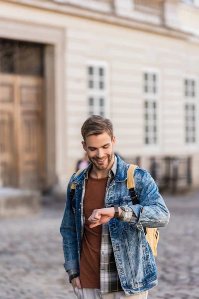 Knappe Man Met Hand Hand Glimlachen Kijken Naar Polshorloge Stad — Stockfoto